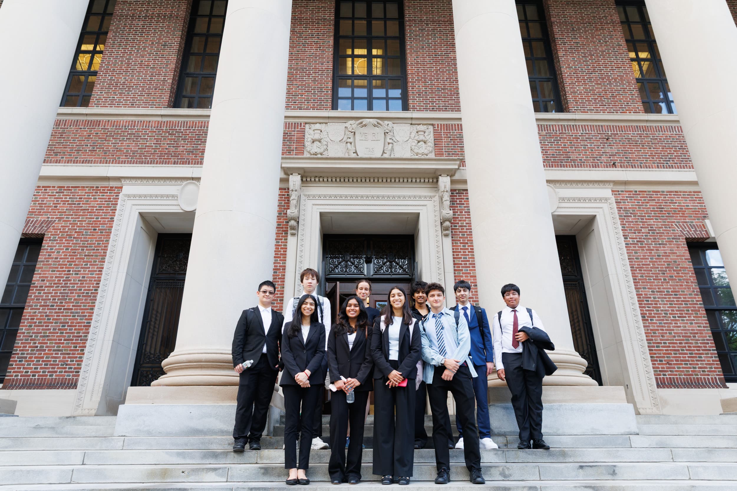 IRO finalists in formal attire on the steps of a Harvard University building